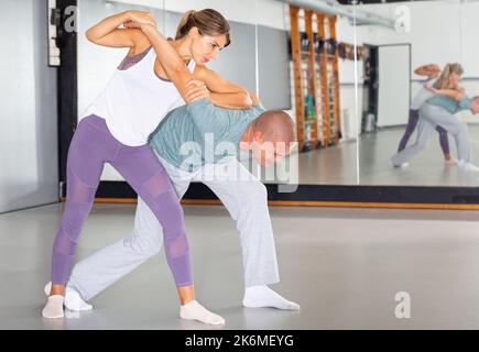 Active girl conducts painful grip on self-defense training in gym Stock Photo