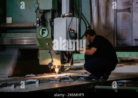 Worker operates drilling machine in factory workshop Stock Photo