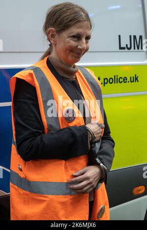 London, UK. 14th October, 2022. A climate activist from Just Stop Oil who had blocked the road in front of New Scotland Yard to call on the UK government to cease issuing oil and gas licences.is pictured under arrest. An activist also spray painted the rotating New Scotland Yard sign outside the building with yellow paint. The Metropolitan Police made 24 arrests on suspicion of wilful obstruction of the highway and/or conspiracy to commit criminal damage. Credit: Mark Kerrison/Alamy Live News Stock Photo