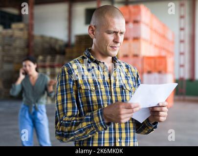 Confident male manager with documents inside large warehouse Stock Photo