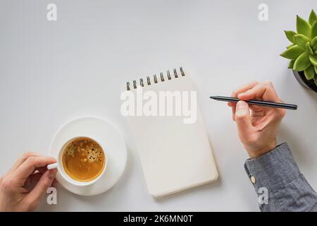 Paper notepad mock-up. Man holding a pen and a coffee, workplace, top view Stock Photo