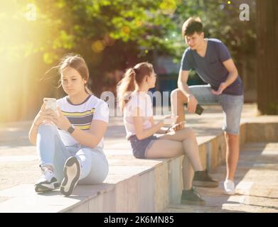 Teenagers are playing on smartphone on street Stock Photo