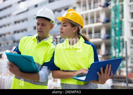 Two engineers are discussing an important project, holding a laptop and an estimate Stock Photo