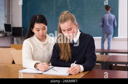 Tired female students during writing notes in classroom Stock Photo