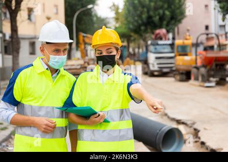 Civil engineers in masks checking work process Stock Photo