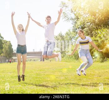 Happy teenagers jumping on the green lawn Stock Photo