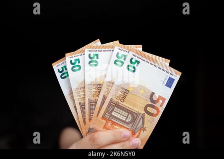 A man holds 100 euro banknotes in his hand on a dark background. cash paper currency, payment, earning and savings, money and finance concept. Empty s Stock Photo