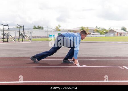 Start Concept. Top view of a Man on Start Line, Get Ready for New Challenge. Metaphor Photo. startup business. an office worker trains at the stadium. Stock Photo