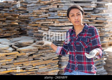 Hispanic woman worker posing with natural stone tile Stock Photo