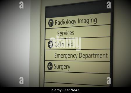 Directional sign in a hospital hallway, directing patients to radiology imaging, cath lab and surgery. Stock Photo