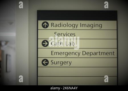 Directional sign in a hospital hallway, directing patients to radiology imaging, cath lab and surgery. Stock Photo