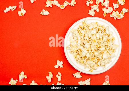 Snack concept, Sweet popcorn in white plate and falling on red background. Stock Photo