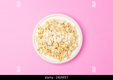 Snack concept, Sweet popcorn in white plate in the middle of pink background. Stock Photo