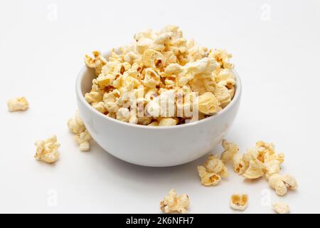 Snack concept, Sweet popcorn in white bowl and falling on white background. Stock Photo