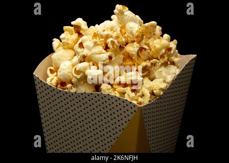 Snack of watching movie concept, Sweet popcorn in paper cup on black background. Stock Photo