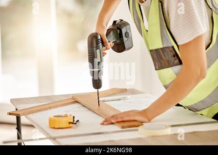 I need to put some nails in this. an unrecognisable construction worker standing alone and using a power drill. Stock Photo