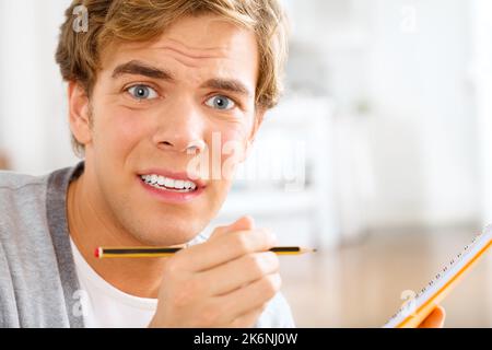 I dont think Ill remember this. a young man looking stressed out while making notes. Stock Photo