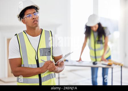 Do we need more supplies. a handsome young contractor standing inside and looking contemplative while using a clipboard. Stock Photo