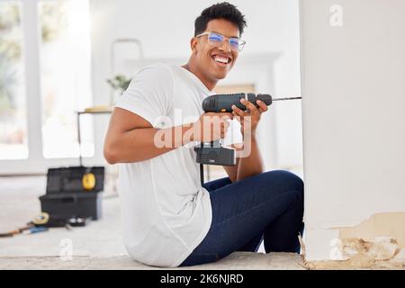 Wait till you see this place when Im done with renovations. a man using a cordless drill on a wall. Stock Photo