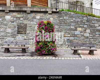 Ischgl, Austria - July 25, 2022: Two benches in Ischgl with inscription: Relax if you can. A colorful floral decoration between them. Stock Photo