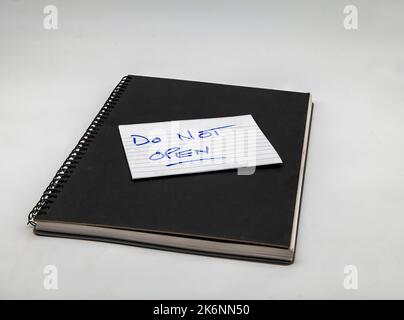 A black book with a note saying not to open isolated on a white background. Stock Photo