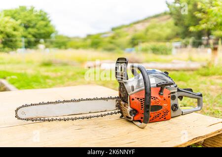 Chainsaw on a wooden table in a garden Stock Photo