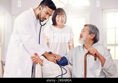 Thank you for coming out, Doctor. a male doctor examining a senior patient with a blood pressure gauge. Stock Photo