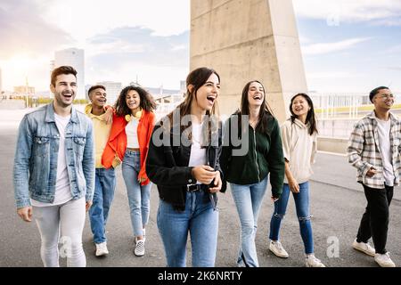 Young group of multiracial friends laughing together hanging out outdoors Stock Photo