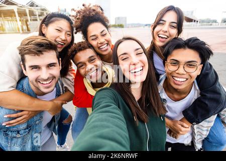 Funny young group of multiethnic friends taking self portrait together outdoors Stock Photo