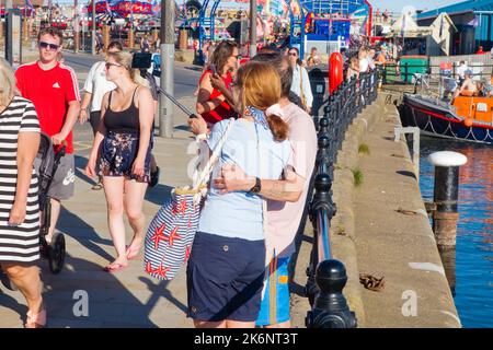 A couple taking a selfie using a stick at the harbourside in Scarborough Stock Photo