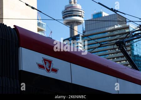 The TTC, Toronto Transit Commission logo is seen on the side of a TTC streetcar with the CN Tower seen in the background. Stock Photo