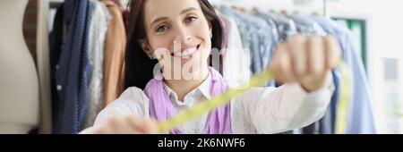 Seamstress in the atelier shows a measuring tape Stock Photo