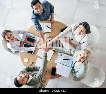 United in their pursuit of success. High angle shot of a group of young businesspeople joining hands in solidarity in a modern office. Stock Photo