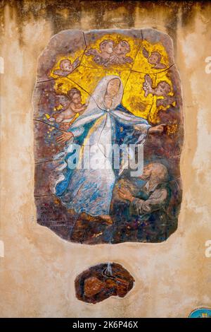 A painting on the wall depicting a monk praying to the Virgin Mary by artist Imelda Bassanello, near the Sanctuary of Savona. Liguria, Italy. Stock Photo