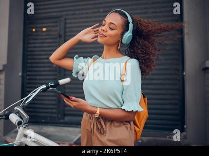 Bicycle, phone and black woman on headphones in city streaming audio, music or podcast. Happy, travel and female from South Africa with bike, 5g Stock Photo