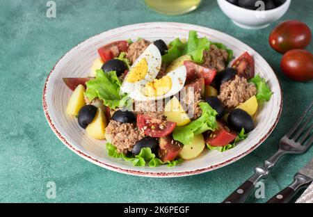 Salad with canned tuna, boiled potatoes, cherry tomatoes, eggs, olives and lettuce, dressed with olive oil Stock Photo