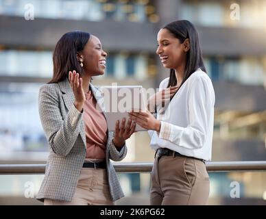 A cheerful spirit creates a cheerful day. two young businesswoman using a digital tablet against a city background. Stock Photo