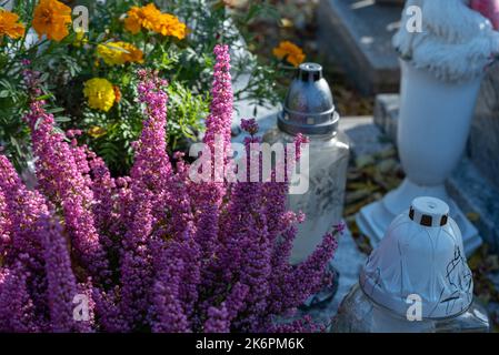 Bunches of artificial flowers in close-up. Faded artificial flowers on the grave. Colorful flowers on the grave. Stock Photo