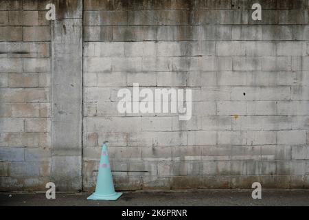 Old gray brick wall and traffic cone in street Stock Photo