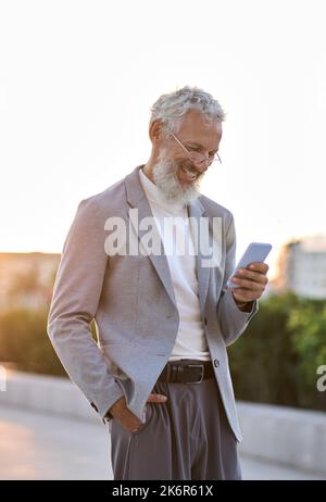 Happy old professional business man holding using phone outdoor, vertical. Stock Photo
