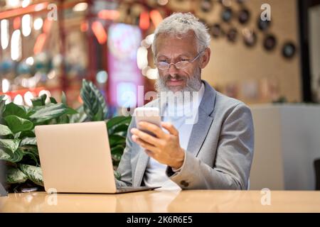 Older business man executive using mobile phone working late in office. Stock Photo