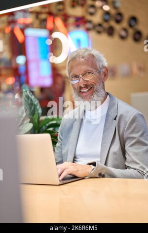 Happy old senior business man using laptop working late on computer. Portrait. Stock Photo