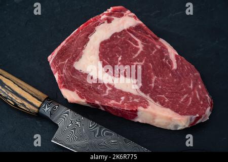 Wagyu Beef Ribeye Steak Raw Dry Aged with Damascus Knife Stock Photo