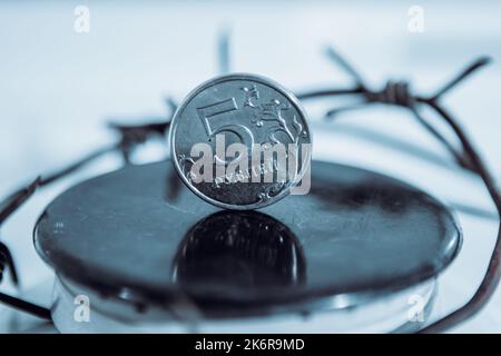 Restrictions causing shortages in gas supplies, burners Gas stove with barbed Wire and ruble coin, concept gas crisis Stock Photo