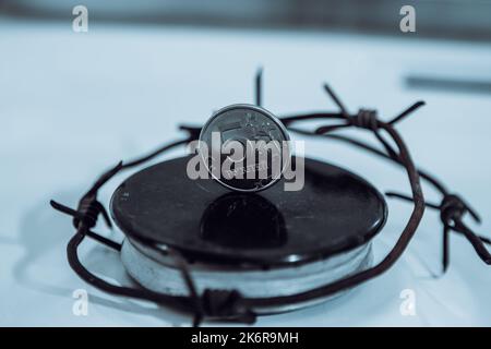 Restrictions causing shortages in gas supplies, burners Gas stove with barbed Wire and ruble coin, concept gas crisis Stock Photo