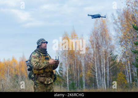 Mercenary soldier launch a reconnaissance drone in a forest. Modern technological methods of reconnaissance and warfare. Stock Photo