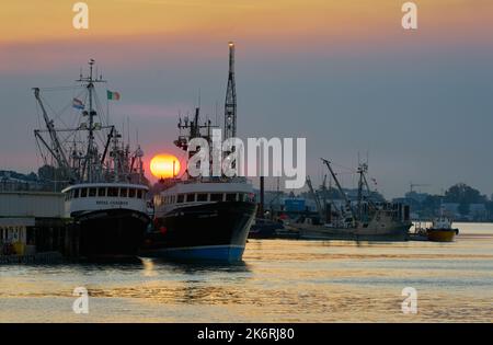 Richmond, British Columbia, Canada – October 15, 2022. Sunrise over Seiners Steveston Harbour. An orange sun rises between fishing boats. Stock Photo