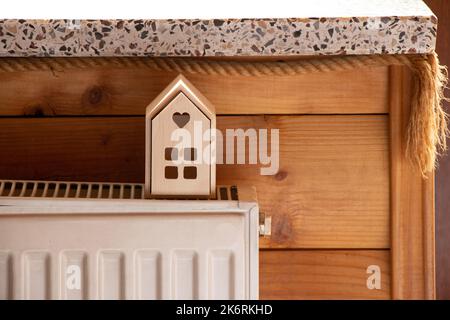 A small wooden house stands on batteries in an apartment near the window, a warm house, central heating Stock Photo
