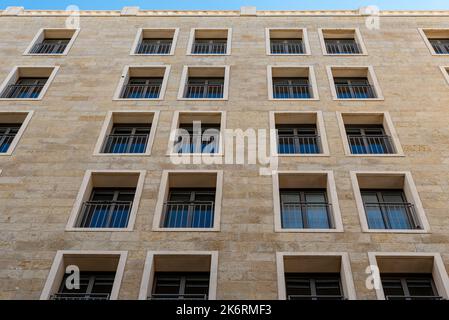 Black long thin rectangular windows in the new building. Many windows dark brown color on the house. stone building with many windows Stock Photo