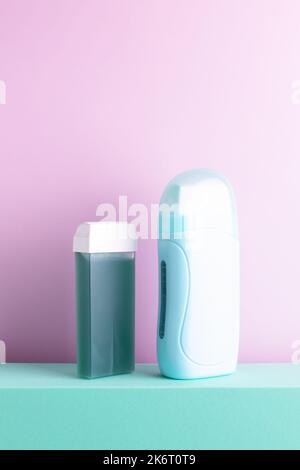 Studio shot of green mint portable depilation wax heater and hair removal green wax roll-on cartridge standing on a decorative podium. Stock Photo